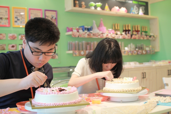 Teenage customers make their own custom-designed cakes at Dan Hana Cake, a do-it-yourself styled store near Yeonshinnae Station in Seoul. (Dan Hana Cake)