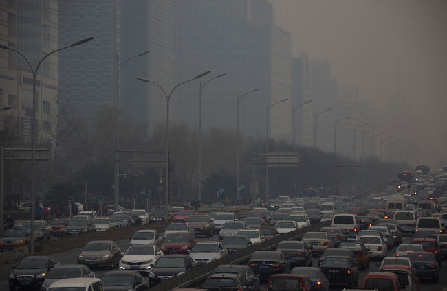 Traffic moves along a street shrouded in haze in Beijing. (Bloomberg)