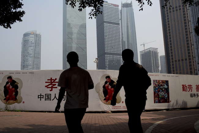 Two pedestrians are seen in front of a public service advertisement promoting the “Chinese Dream” slogan unveiled by President Xi Jinping in the Zhujiang New Town district of Guangzhou, China. (Bloomberg)