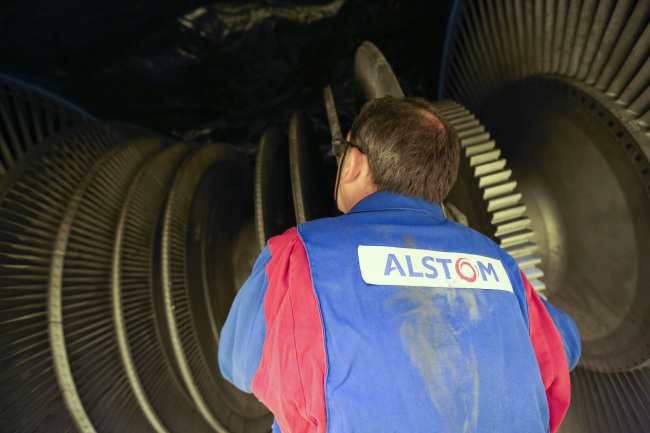 An employee inspects a turbine at Alstom SA’s power plant turbine refurbishment facility in Rugby, England. ( Bloomberg)