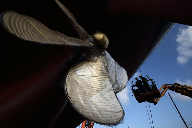 Employees work on an elevated work platform near the propeller of a ship under construction at the Hyundai Samho Heavy Industries Co. shipyard in Yeongam, South Jeolla Province. (Bloomberg)