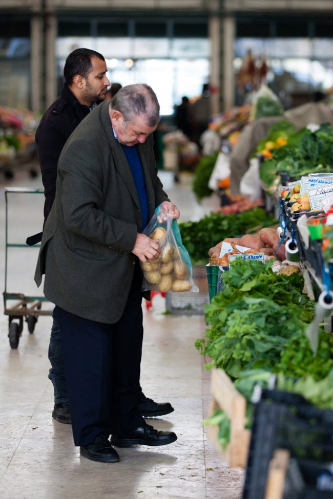 An elderly customer selects potatoes from a stall at Ribeira market in Lisbon. (Bloomberg)