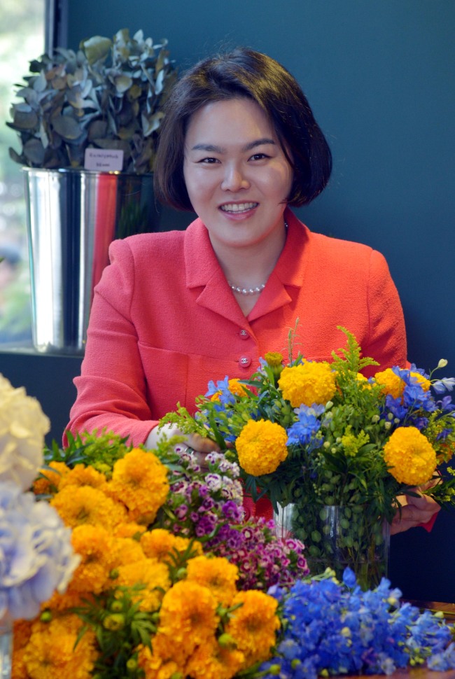 Florist Audrey Oh arranges a spring bouquet of marigolds and blue delphiniums in her new shop, Audrey Flowers, in Seoul. (Kim Myung-sub/The Korea Herald)