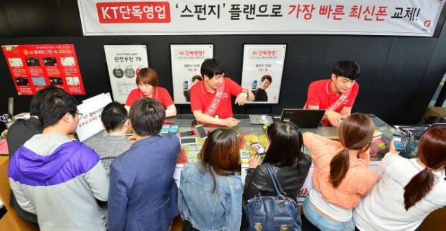 A KT dealer serves customers at the mobile carrier’s retail shop in Seoul. (KT)