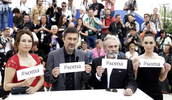 Actress Demet Akbag (from left), director Nuri Bilgle Ceylan, actor Haluk Bilginer and actress Melisa Soezen pose with signs reading “#soma,” a reference to Turkey’s worst mining incident, which took place last week, during a photo call for “Winter Sleep” at the Cannes Film Festival in Cannes on Friday. ( AP-Yonhap)