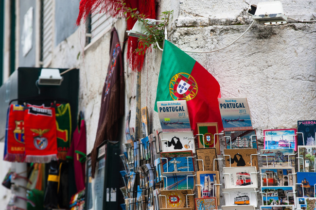 A Portuguese national flag hangs above a display of postcards and tourist guide books outside a souvenir store in Lisbon. (Bloomberg)