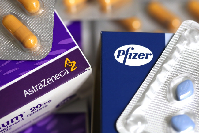 The logos of Pfizer Inc. and AstraZeneca Plc are seen on boxes of pharmaceutical products. (Bloomberg)