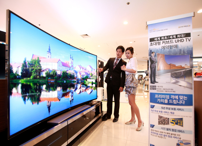 Models look at Samsung Electronics’ 78-inch curved ultrahigh-definition TV, which was unveiled in April. (Samsung Electronics)