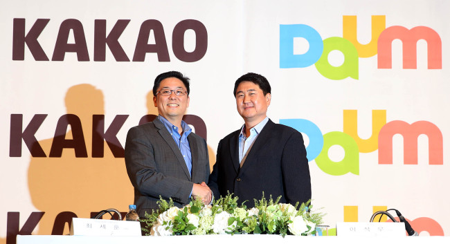 Daum Communications chief executive Choi Sae-hoon (left) and Kakao co-CEO Lee Sir-goo pose at a press meeting where the two sides announced the merger of the Internet portal and mobile messenger firms. (Yonhap)
