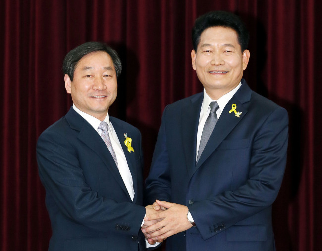 Incheon Mayor Song Young-gil (right) shakes hands with Saenuri Party candidate Yoo Jeong-bok during an event to pledge fair campaigns earlier this month. (Yonhap)