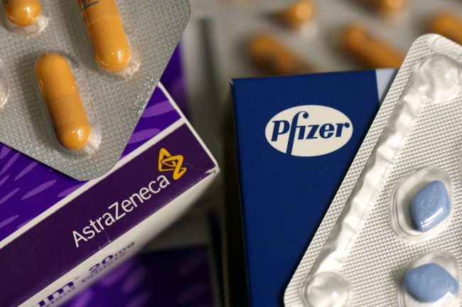 Logos of Pfizer and AstraZeneca are seen on boxes of pharmaceutical products in London. ( Bloomberg)