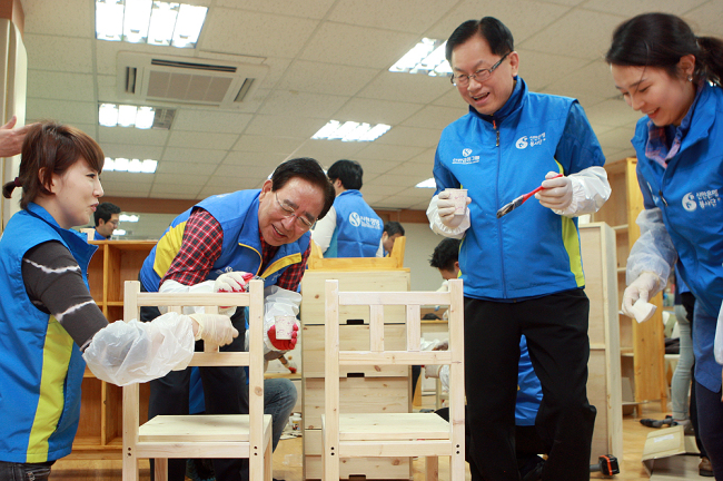 Shinhan Financial Group chairman Han Dong-woo (second from left) participates in the corporate volunteer project for building eco-friendly furniture to distribute to underprivileged households. (Shinhan Financial Group)