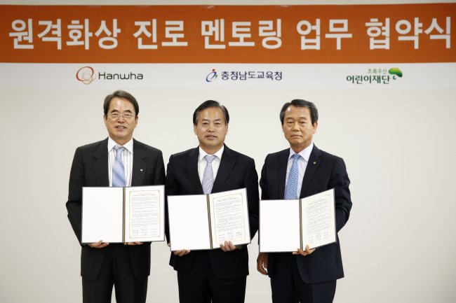 Hanwha S&C CEO Jin Hwa-keun (right), ChildFund Korea president Lee Je-hoon (left) and vice education chief of South Chungcheong Province Jeon Chan-hwan pose together in Seoul on Tuesday after signing an agreement to launch an online mentoring program for teenage students in rural areas. (Hanwha Group)