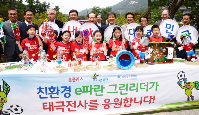 Homeplus CEO Do Sung-hwan (left, back row) and eParan Foundation’s board of directors head Lee Seung-han (sixth from left, back row) poses with kids and participants of a painting contest hosted by eParan on Sunday in central Seoul to celebrate World Environment Day on June 5. EParan is a social contribution organization run by Homeplus. (Park Hyun-koo/The Korea Herald)