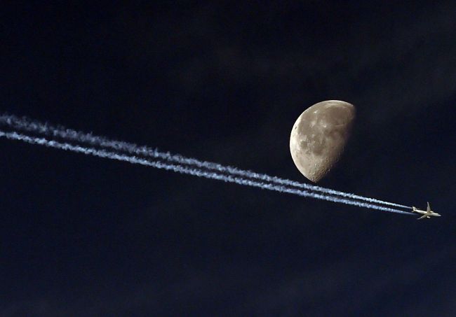 A jet passes in front of the moon in Algiers, Algeria. (AFP-Yonhap)