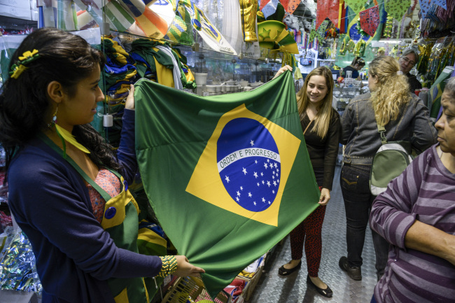 Customers hold up a Brazilian flag at a shop in Sao Paulo, Brazil. (Bloomberg)