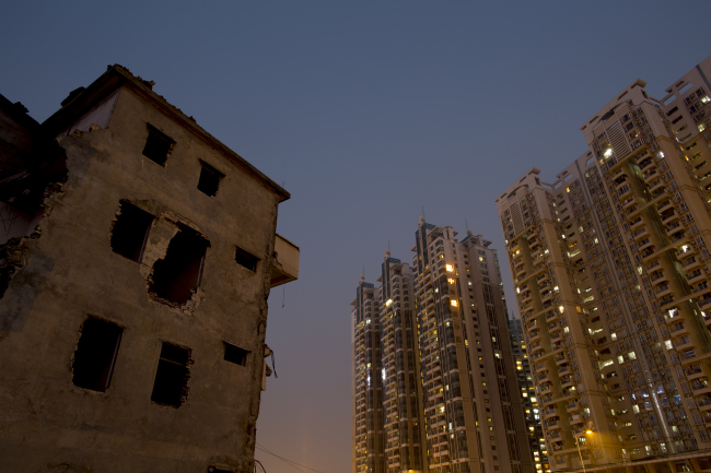 A partially demolished residential building (left) stands next to a Poly Real Estate Group Co. residential complex in the Zhujiang New Town district of Guangzhou, Guangdong province, China. (Bloomberg)