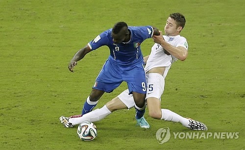 Italy's Mario Balotelli, left, challenges for the ball with England's Gary Cahill during the group D World Cup soccer match between England and Italy at the Arena da Amazonia in Manaus, Brazil, Saturday, June 14, 2014. (Yonhap-AP)