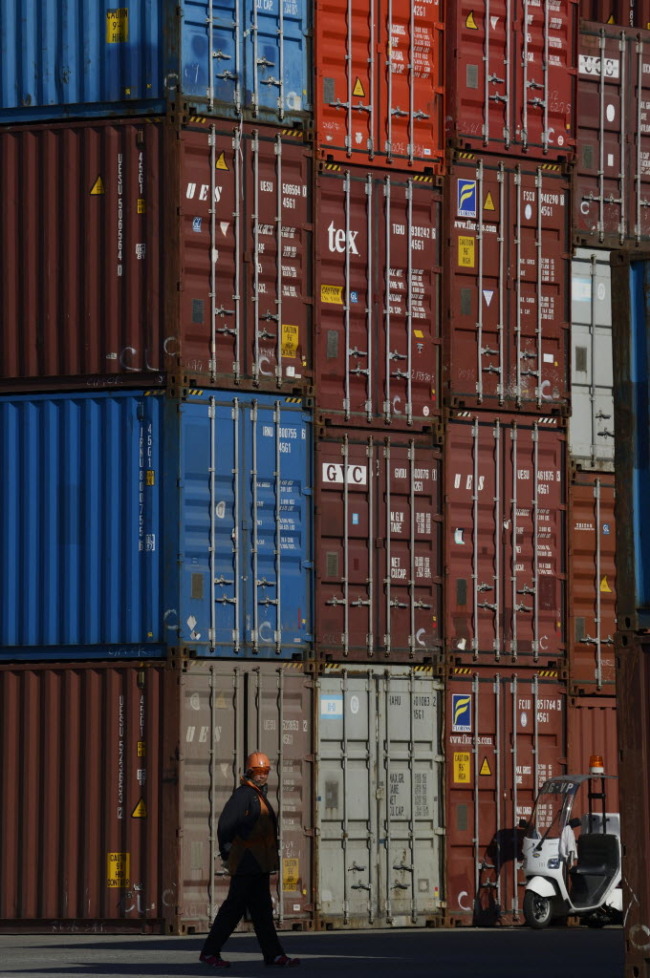 A worker walks past stacked containers at a shipping terminal in Yokohama City, Japan. (Bloomberg)