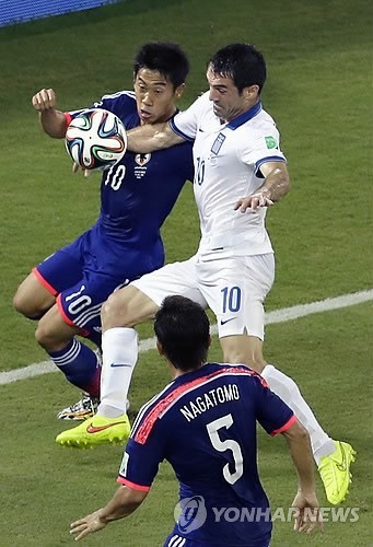 Japan's Shinji Kagawa, left, and Greece's Giorgos Karagounis challenge for the ball during the group C World Cup soccer match between Japan and Greece at the Arena das Dunas in Natal, Brazil, Thursday, June 19, 2014. (AP-Yonhap)
