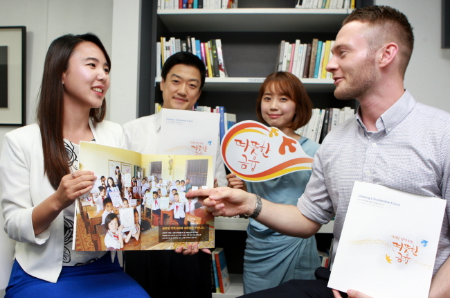 Shinhan Financial Group employees display the group’s annual CSR report for 2013, titled “Compassionate Finance.” (Shinhan Financial Group)