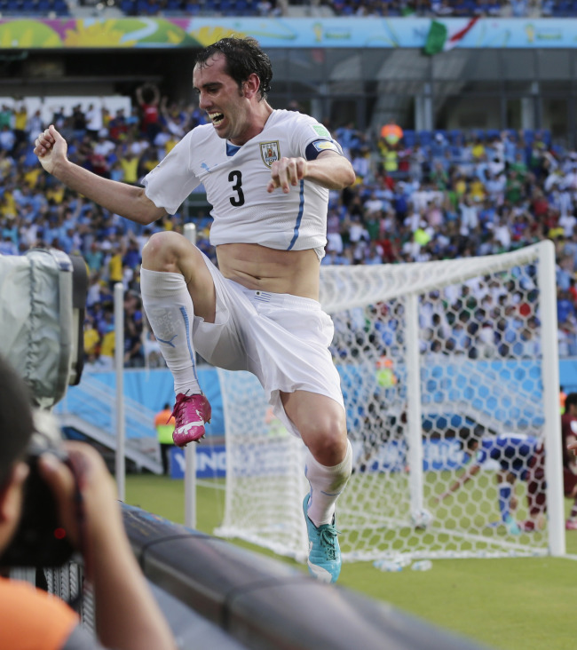 Uruguay's Diego Godin jumps over a barricade after scoring his side's first goal during the group D World Cup soccer match between Italy and Uruguay at the Arena das Dunas in Natal, Brazil, Tuesday. (AP-Yonhap)