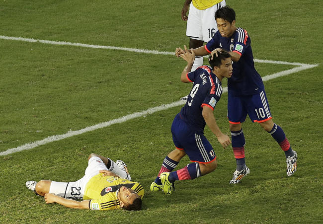 Japan forward Shinji Okazaki, middle, celebrates his goal with Shinji Kagawa, right, past Colombia defender Carlos Valdes during the group C World Cup soccer match between Japan and Colombia at the Arena Pantanal in Cuiaba, Brazil, Tuesday. (AP)