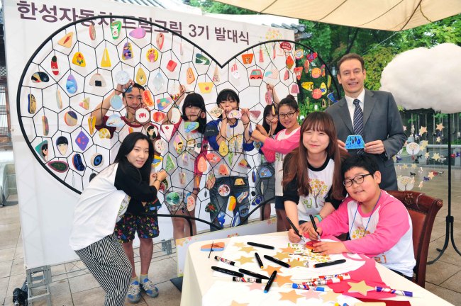 Han Sung Motor CEO Ulf Ausprung (right) and art students of the company’s “Dream Gream Project” pose next to their work titled “Dynamic: Connecting the Hearts” during an event celebrating the program’s third anniversary at Korea House in Pil-dong, central Seoul, June 23. (Han Sung Motor)