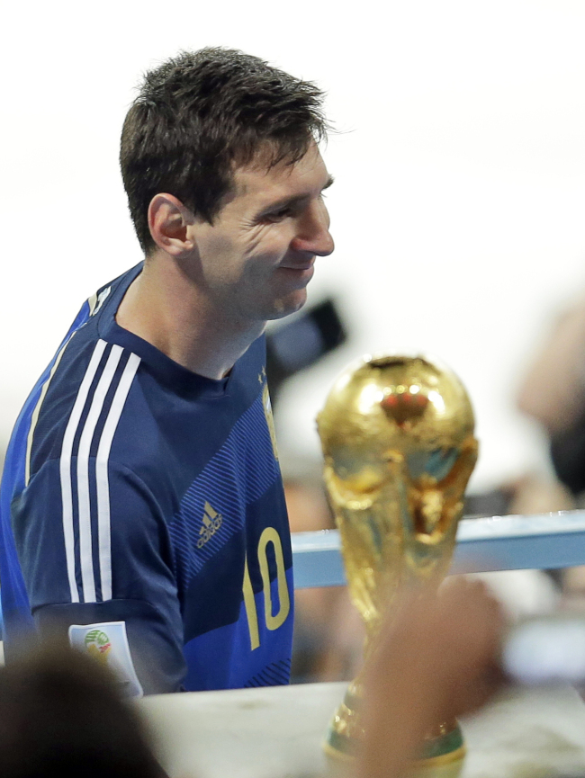 Argentina's Lionel Messi walks by the World Cup trophy as he goes on the tribune to collect the second place trophy after the World Cup final soccer match between Germany and Argentina at the Maracana Stadium in Rio de Janeiro, Brazil, Sunday, July 13, 2014. Germany won 1-0.(AP-Yonhap)