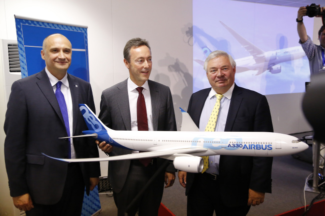 Eric Schulz (left), president of civil large engines at Rolls Royce Holdings Plc; Fabrice Bregier (center), chief executive officer of Airbus; and John Leahy, chief operating officer of Airbus Group NV, pose with a model Airbus A330-800neo aircraft, during a news conference during the Farnborough International Airshow in Farnborough, England, Monday. (Bloomberg)