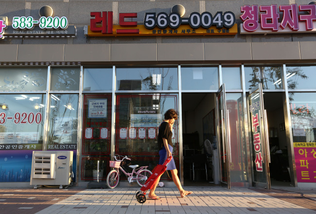 A pedestrian walks past real estate agencies at Cheongna International City in Incheon. (Bloomberg)