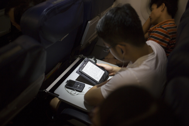 A passenger reads on an Amazon.com Inc. Kindle tablet on board a VietJet Air aircraft at Noi Bai International Airport in Hanoi, Vietnam.(Bloomberg)