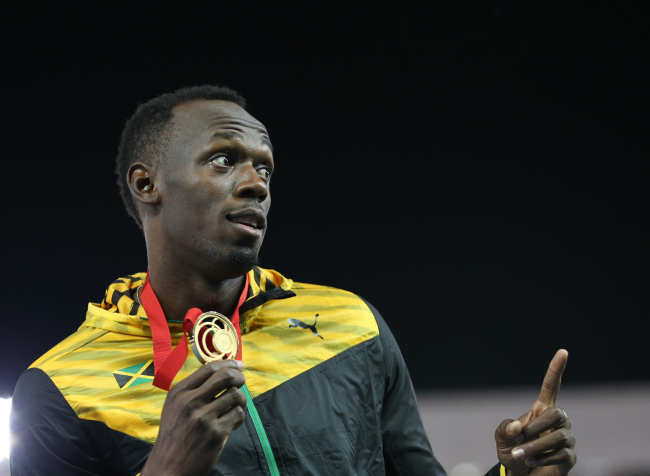 Usain Bolt poses with his gold medal Saturday. (AP-Yonhap)