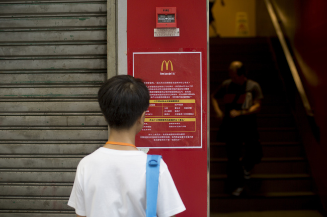 A man reads a food safety information sign displayed outside a McDonald’s in Hong Kong. (Bloomberg)