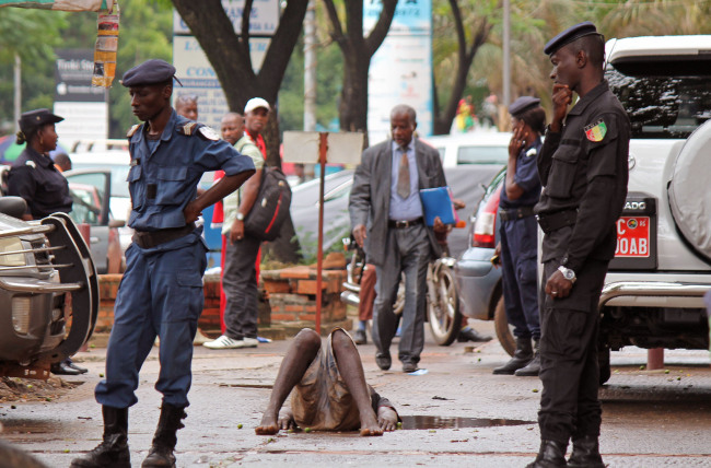 Guinean Police secure the area around a man who collapsed in a puddle of water on the street, while people avoid him for fear that he is infected with the Ebola virus in the city of Conakry, Guinea, Wednesday. The man lay in the street for several hours before being taken to an Ebola control center for assessment. (AP-Yonhap)