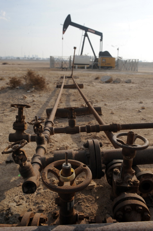 An oil pump operates near a valve assembly in the Awali oil field in Bahrain. (Bloomberg)