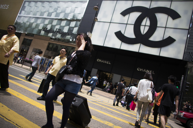 Pedestrians and shoppers cross the street in front of a Chanel store in the Tsim Sha Tsui area of Hong Kong. (Bloomberg)