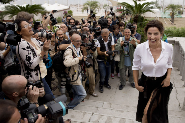 Italian actress Luisa Ranieri (right), who will host the 71st Venice Film Festival, laughs as she walks up stairs surrounded by photographers during a photo call in Venice, Italy, Tuesday. The 71st edition of the festival opens on Wednesday and runs until Sept. 6. (AP-Yonhap)