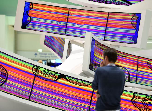 A visitor stands in front of curved television sets Electronics’ booth during the IFA consumer electronics trade fair in Berlin on Sept. 5. (AFP-Yonhap)