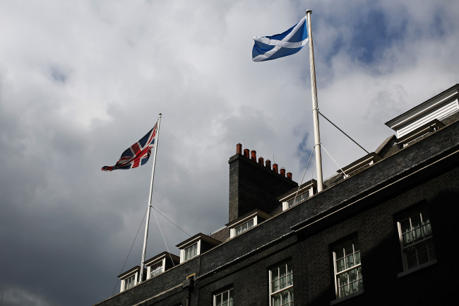A Union flag (left), the national flag of the United Kingdom, and a St. Andrew’s or Saltire flag, the national flag of Scotland, fly from flagpoles above buildings in Downing Street in London on Wednesday. (Bloomberg)