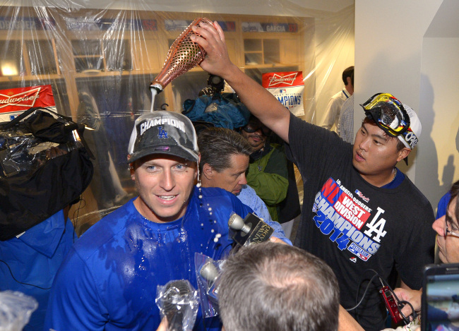 Los Angeles Dodgers’ A.J. Ellis (left) is doused with champagne by Ryu Hyun-jin after they defeated the San Francisco Giants and clinched the National League West Division title on Wednesday. (AP-Yonhap)