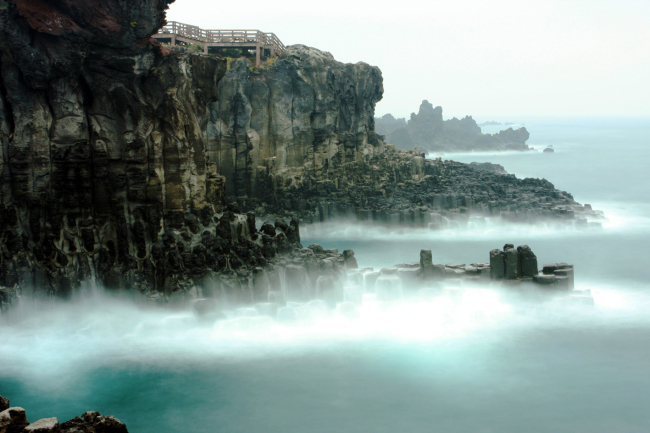 The Jusangjeolli Cliffs, at the southern coast of Jejudo Island, offer a rare glimpse into the stunning volcanic rock formations of hexagonal columns, one of the scenic sites showcasing the island’s natural beauty.