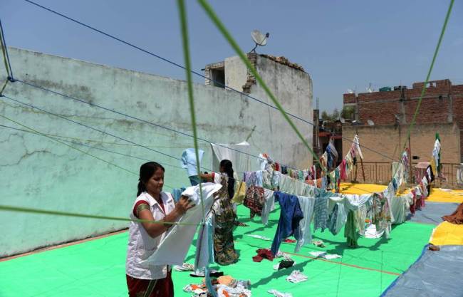 Employees hang just-washed donated cotton clothes that will be used to make cloth sanitary napkins at nonprofit organization Goonj in New Delhi. (AFP)