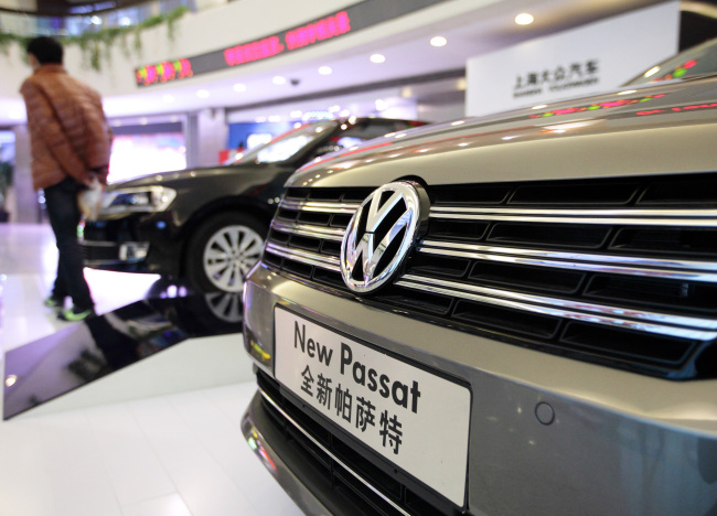 A visitor walks past Volkswagen Passat sedans displayed inside the Oriental Pearl Tower in the Pudong area of Shanghai. (Bloomberg)