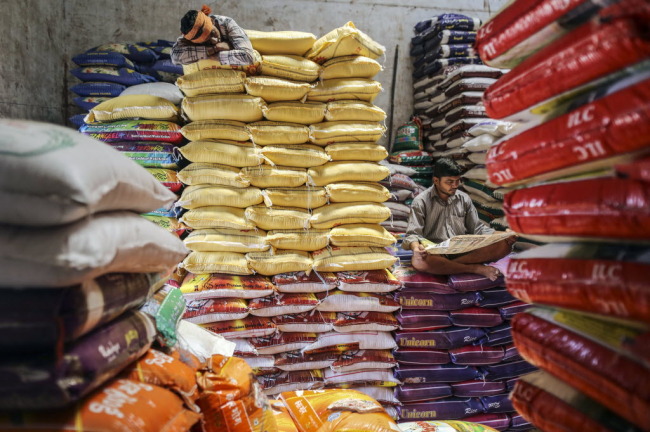 Workers sit and lie on stacked bags of rice at a wholesale market in Mumbai, India. (Bloomberg)