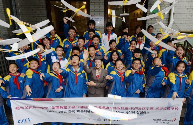 An Asiana flight attendant and students fly paper airplanes to celebrate the “sisterhood” between their school and the airline in Hangzhou, eastern China, Tuesday. (Joint Airport Press Corps)