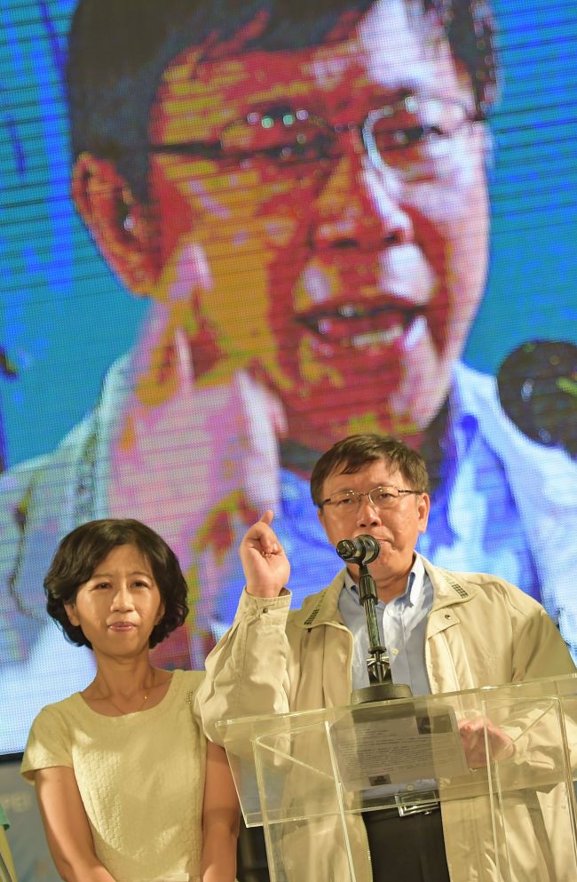 Newly elected independent Taipei Mayor Ko Wen-je (right) speaks next to his wife Chen Pei-chi in front of a giant screen near his campaign headquarters in Taipei on Friday. (AFP-Yonhap)