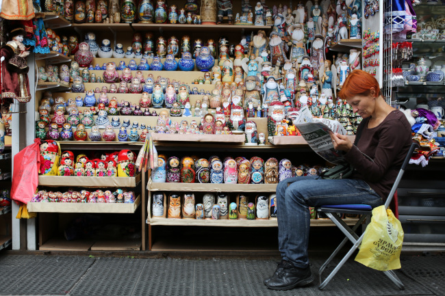 A vendor reads a newspaper beside a souvenir stand selling matryoshka dolls in St. Petersburg, Russia. (Bloomberg)