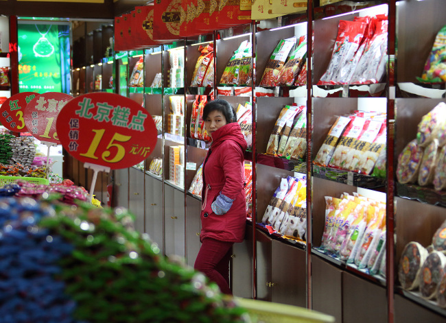 A sales clerk waits for customers at a store selling packaged foods on Qianmen Street in Beijing. (Bloomberg)