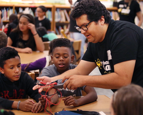 Valencia College student Andres Vera (right) demonstrates how to test the electronics of a “solar suitcase” to students at Tildenville Elementary School in Winter Garden, Florida, on Nov. 7. (Orlando Sentinel/TNS)